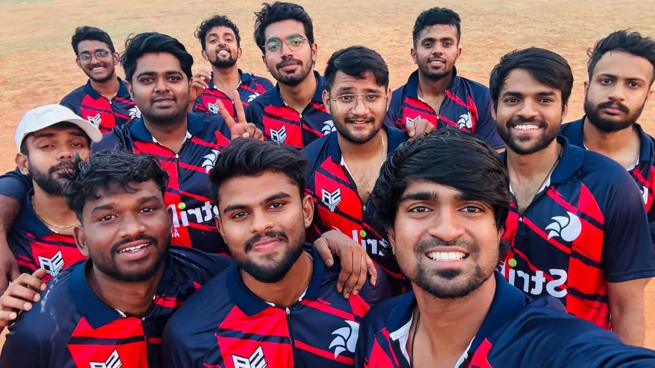 Group selfie of a cricket team in navy jerseys with red diagonal panels, an AE crest and the Strike logo on the chest
